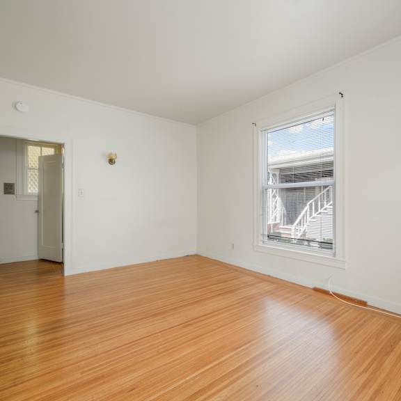 a room with wooden floors and a window showing a building outside.