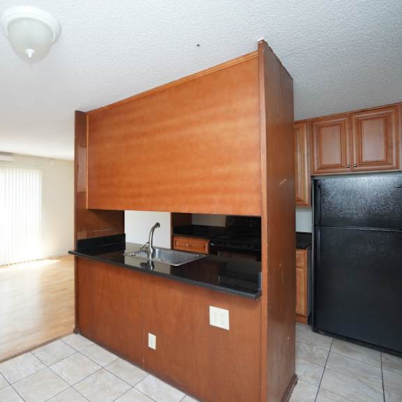 a kitchen with wooden cabinets and a black fridge.