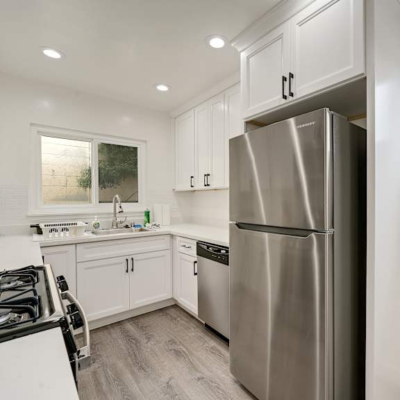 a modern kitchen with a stainless steel refrigerator and a black gas stove.
