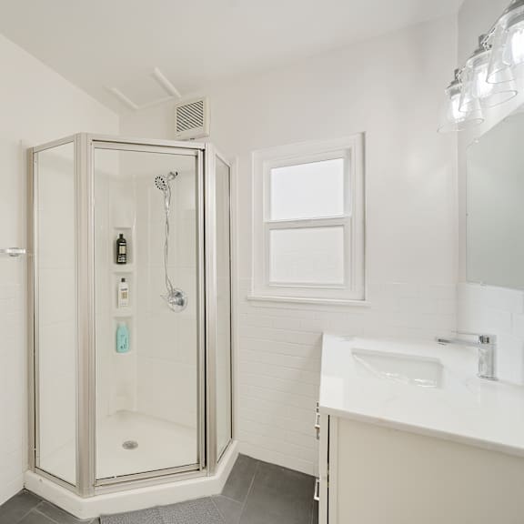 a white bathroom with a glass shower stall and a toilet paper holder.