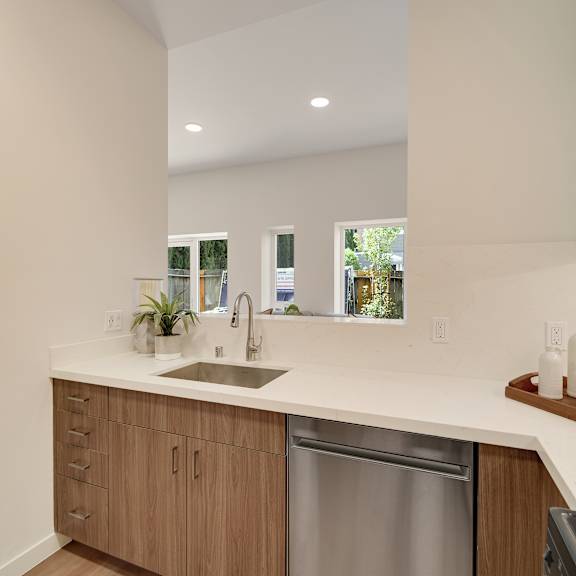 a modern kitchen with a stainless steel dishwasher and wooden cabinets.