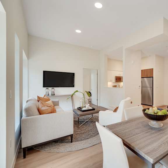 a modern living room with a white couch and a wooden dining table.