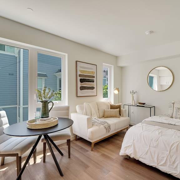 a bedroom with a white bed and a round mirror on the wall.