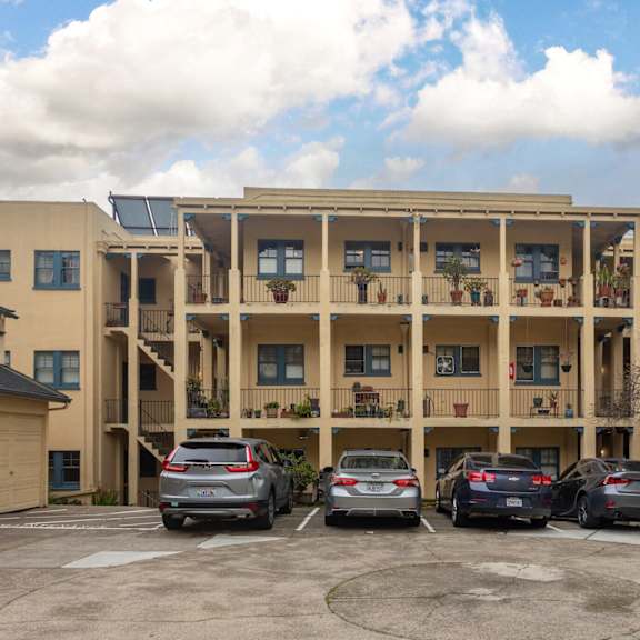 an apartment building with cars parked in a parking lot