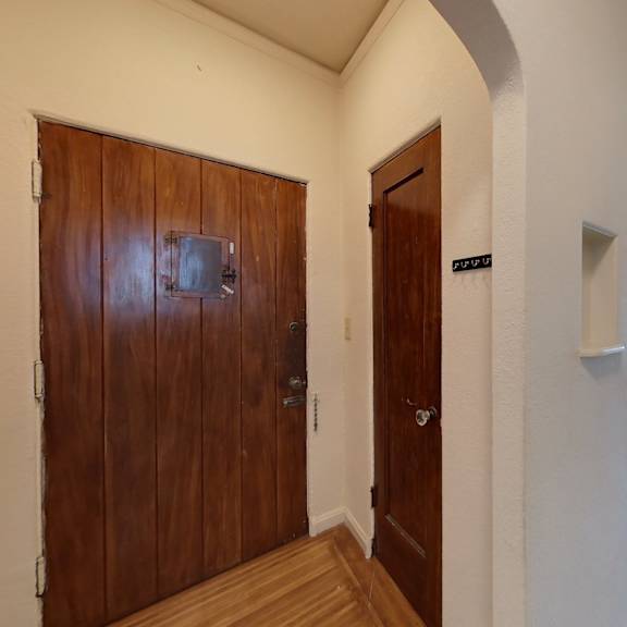 a hallway with a brown door on the left and a white door on the right.