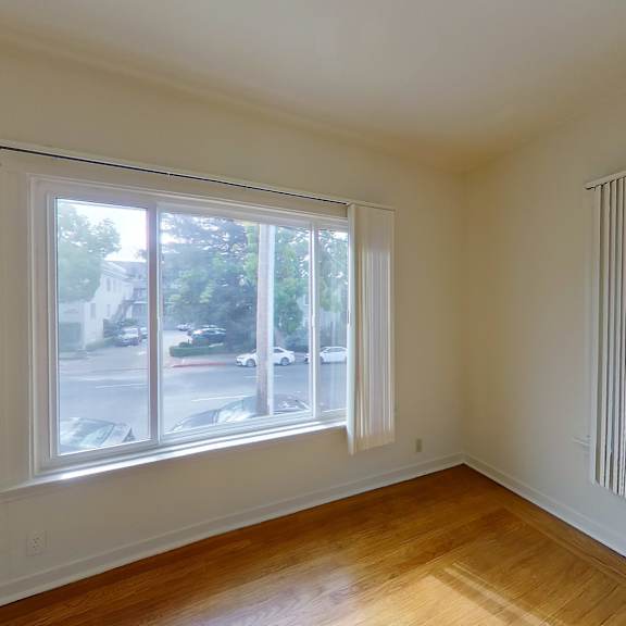 a room with a large window and wooden floors.