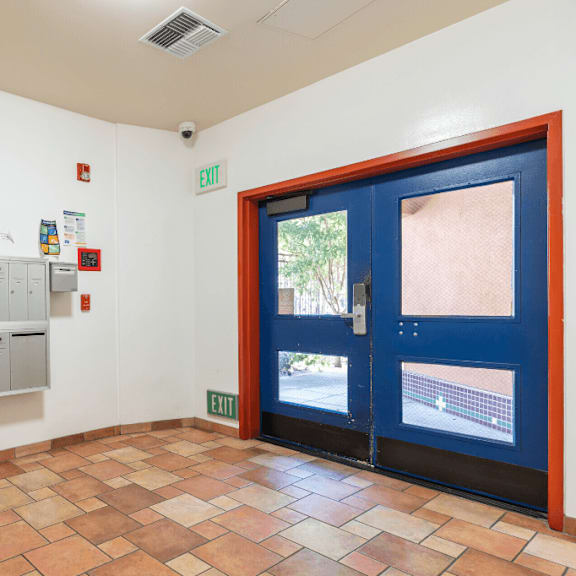 a hallway with a blue door and a wall of lockers.