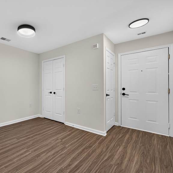 a room with white doors and brown flooring.