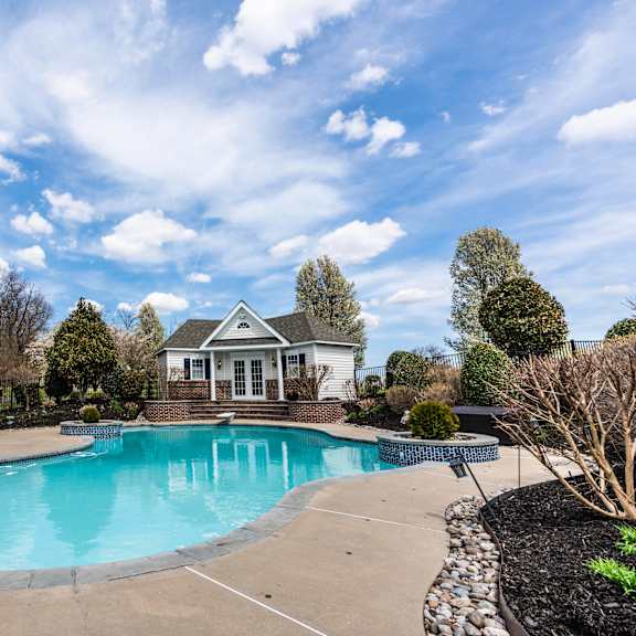 a large swimming pool in a backyard with a house in the background.