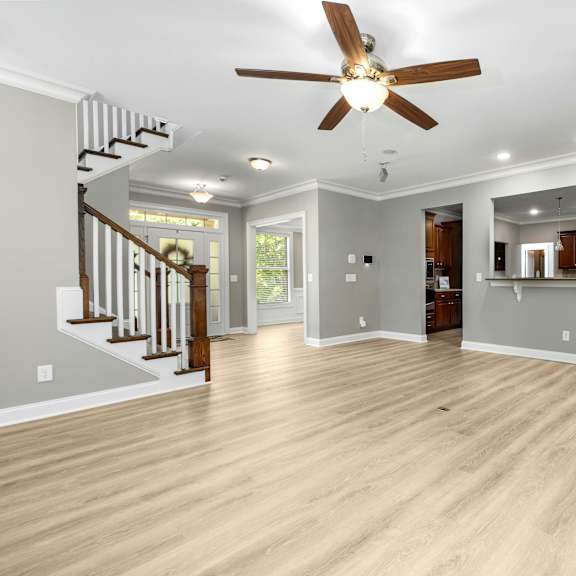 a spacious living room with a ceiling fan and hardwood floors.