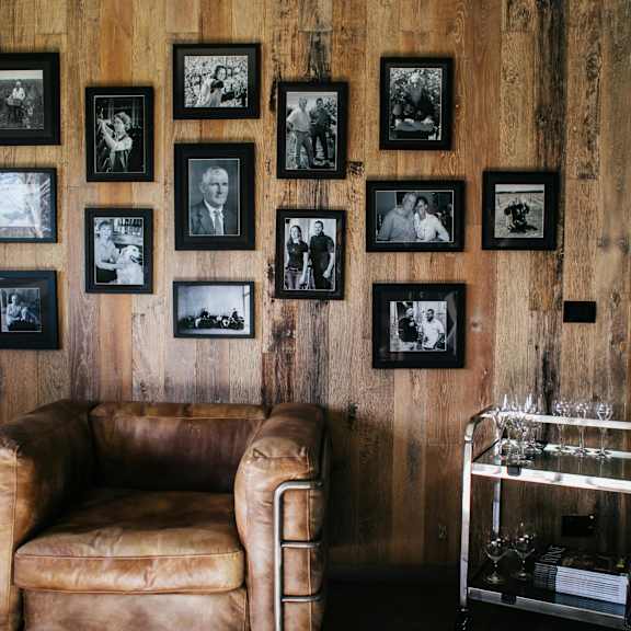 a leather sofa sits in front of a wall of framed photos.