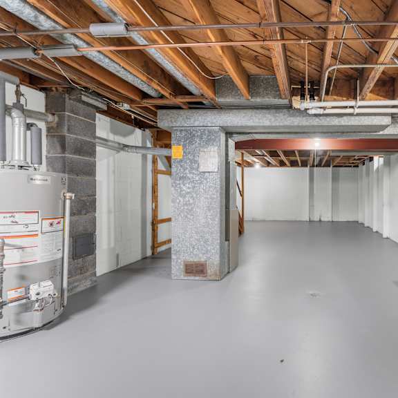 a spacious unfinished room with a concrete floor and exposed ceiling structure.