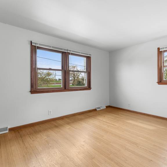 a room with wooden floors and two windows.
