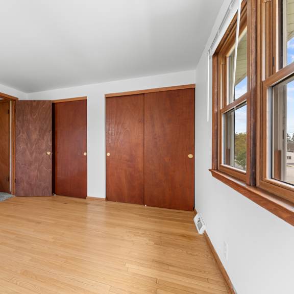 a room with wooden floors and two brown doors.