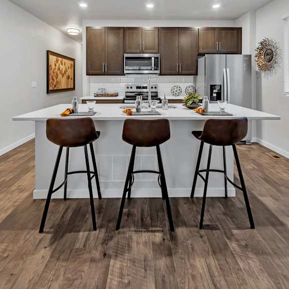 a kitchen with brown bar stools and a white countertop.