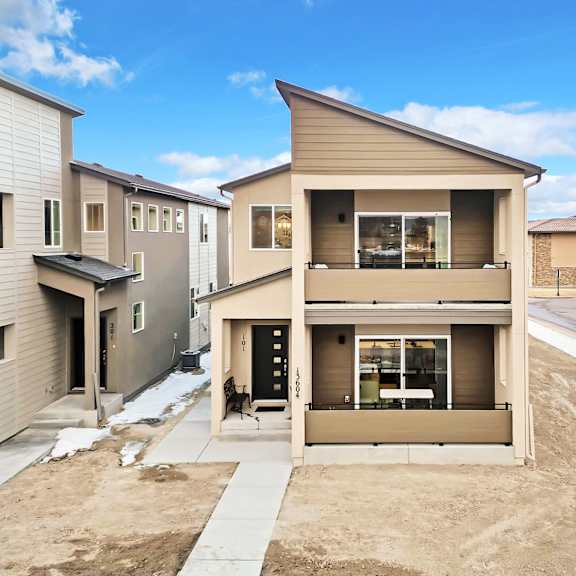 a modern two-story house with a garage is surrounded by other houses.