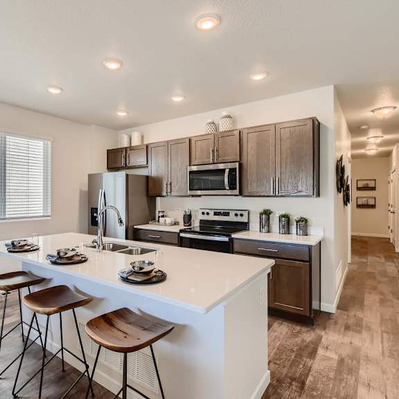 modern kitchen with island and stools in front of stainless steel appliances