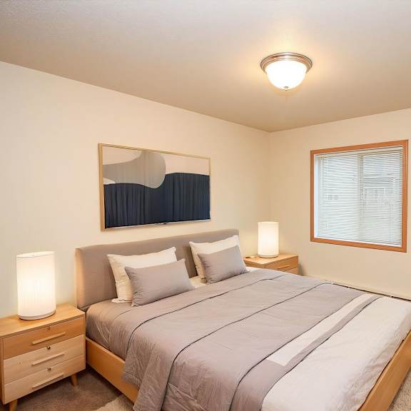 a bedroom with a bed, nightstand, and window.