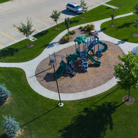 a playground with a green slide and a white fence.