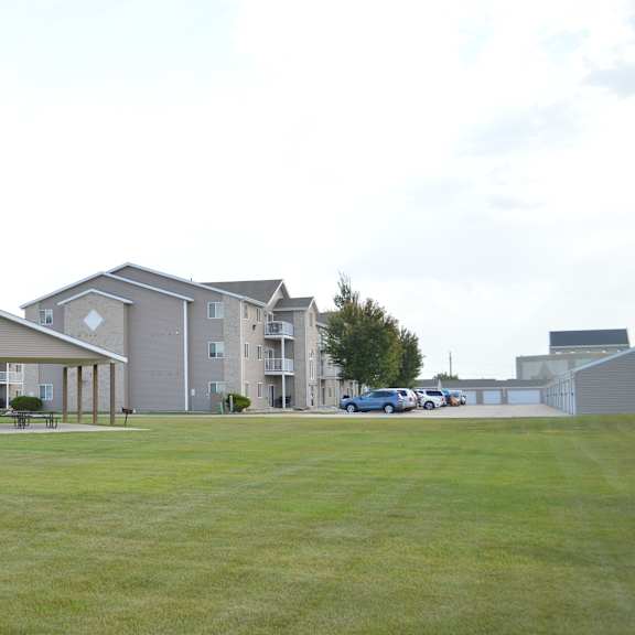 a large grassy field in front of apartment buildings.