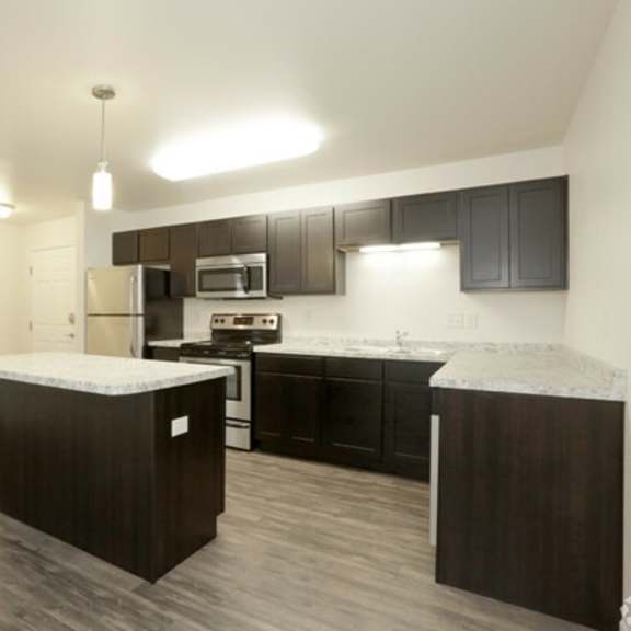 a modern kitchen with dark wood cabinets and a white countertop.