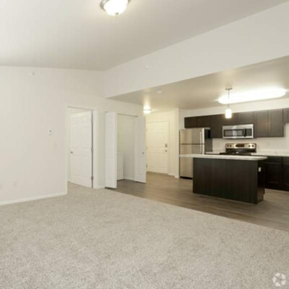 a spacious living room with a kitchen area in the background.
