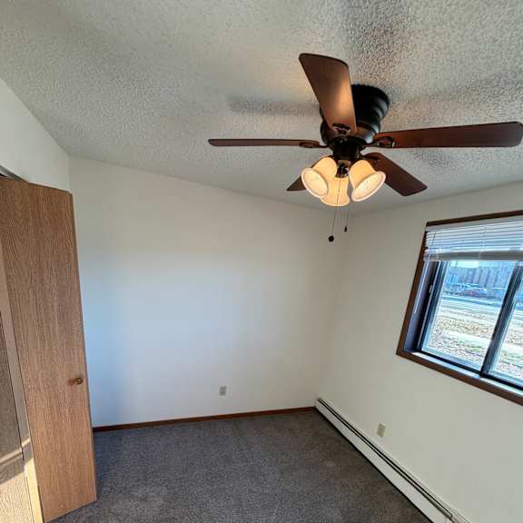 a ceiling fan with lights is mounted on a white wall above a wooden table.