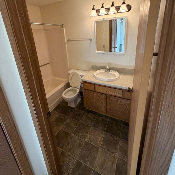 a bathroom with a toilet, sink, and mirror.