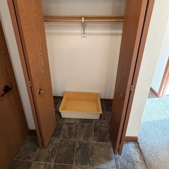 a wooden shelf with a cabinet and a pipe running along the wall.