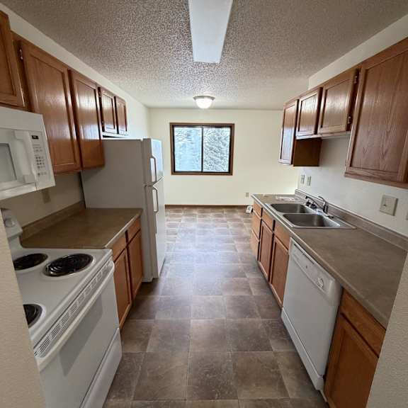 a kitchen with a white fridge, a washing machine and a dishwasher.