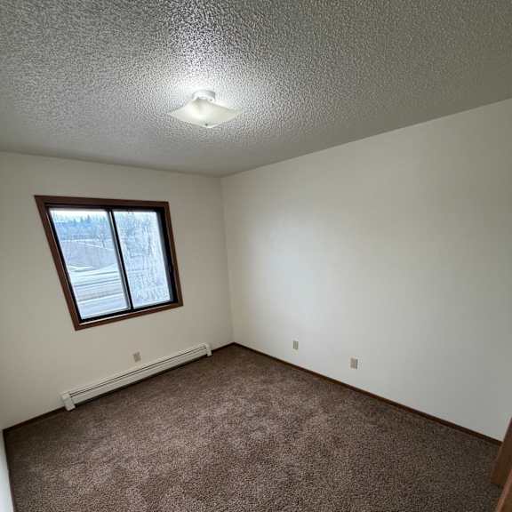 a small window in a room with a brown carpet.
