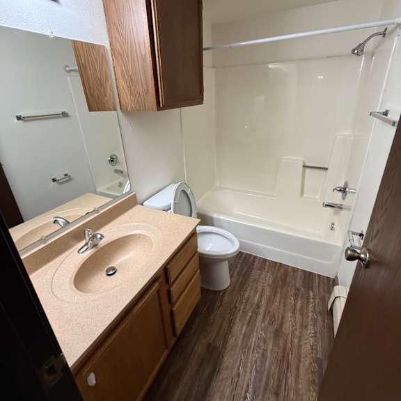 a bathroom with a toilet, sink, and wooden cabinetry.