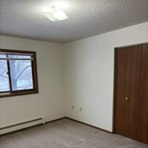 a room with a carpeted floor, a window, and a wooden door.