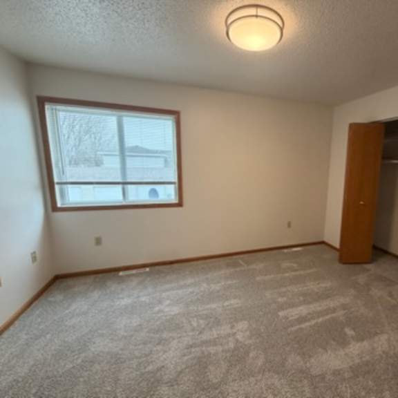 a room with a grey carpet and a window.