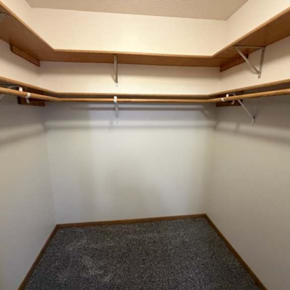 a room with a carpeted floor and a wall with a shelf.