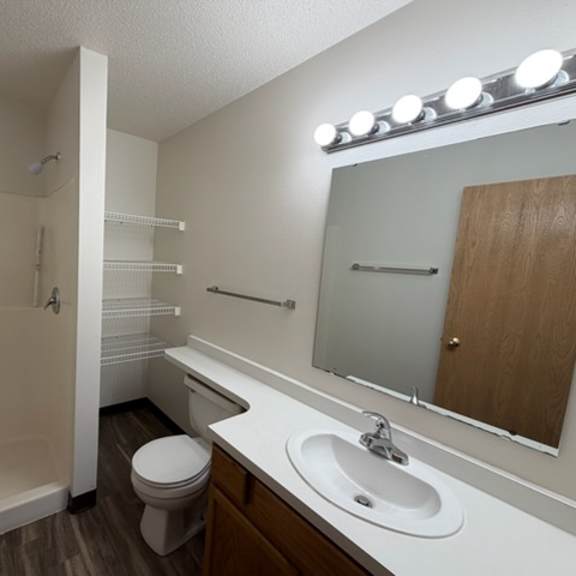 a small bathroom with a toilet, sink, and a shower.