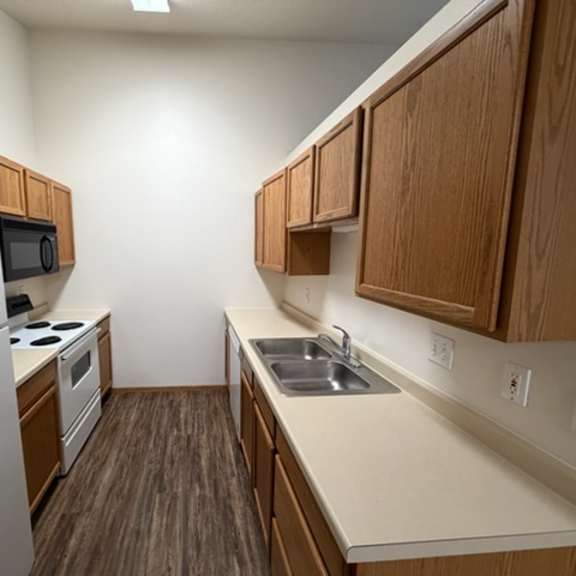 a kitchen with a refrigerator, microwave, oven, sink and cabinets.