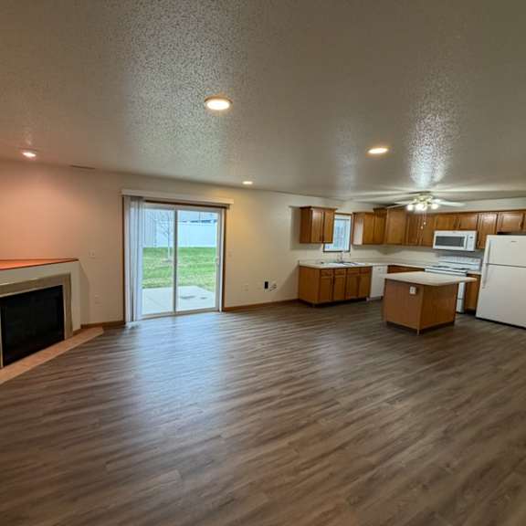 a spacious living room with wood flooring and a fireplace.
