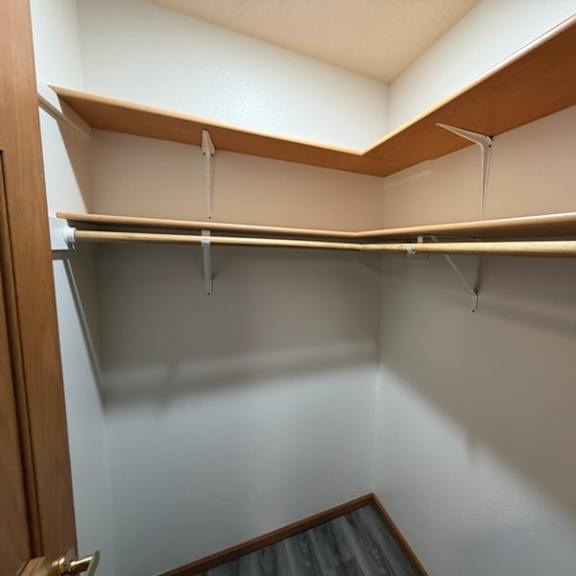 a small, empty closet with a wooden shelf above the hanging rod.