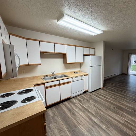 a kitchen with white cabinets and a wooden floor.