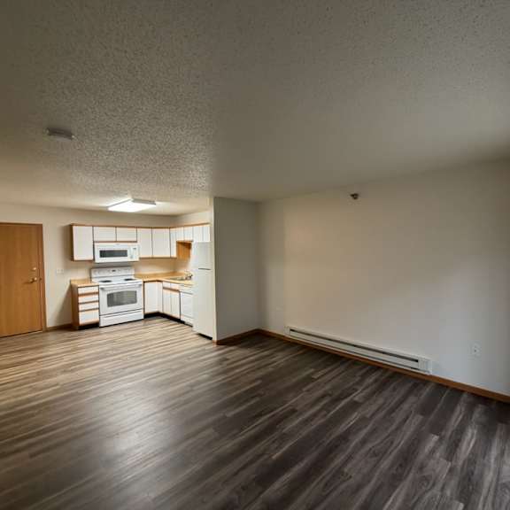 a kitchen with white appliances and wooden floors.