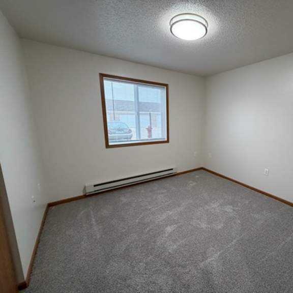a room with a window and a grey carpet.