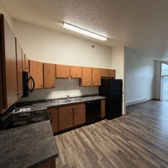 a kitchen with wooden cabinets and a black refrigerator.