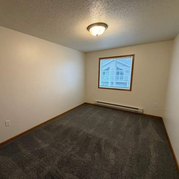 a room with a window and a grey carpet.