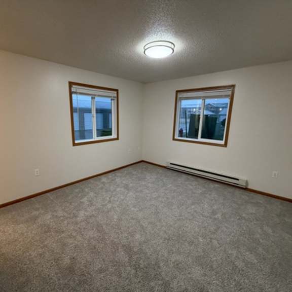 a room with a carpeted floor and two windows.