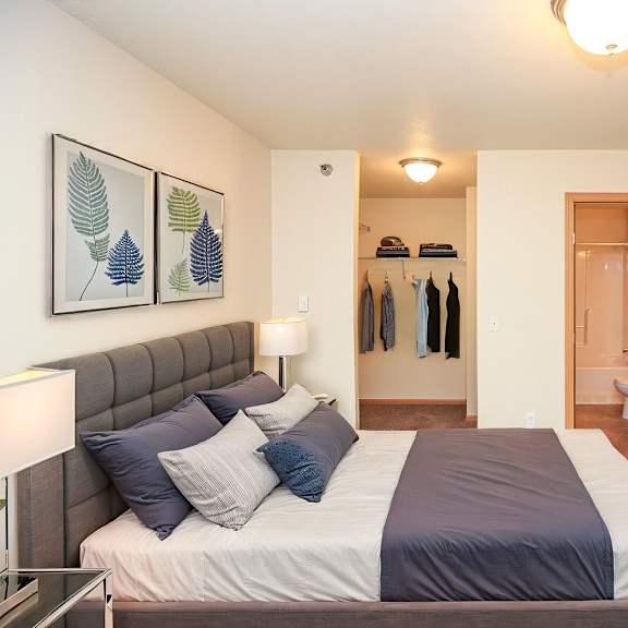 a bedroom with a bed, a lamp, and a coat rack.