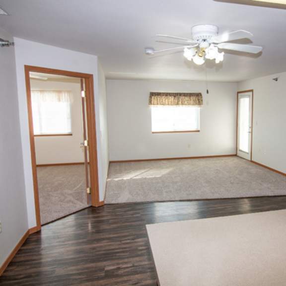 a room with a ceiling fan and a rug on the floor.