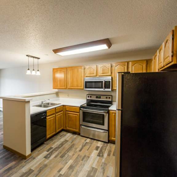 a kitchen with wooden cabinets and a black refrigerator.