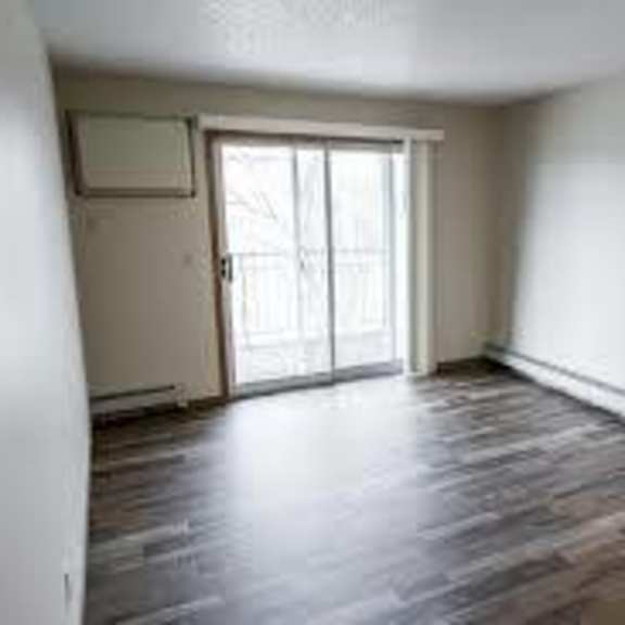 a room with a sliding glass door and wood flooring.