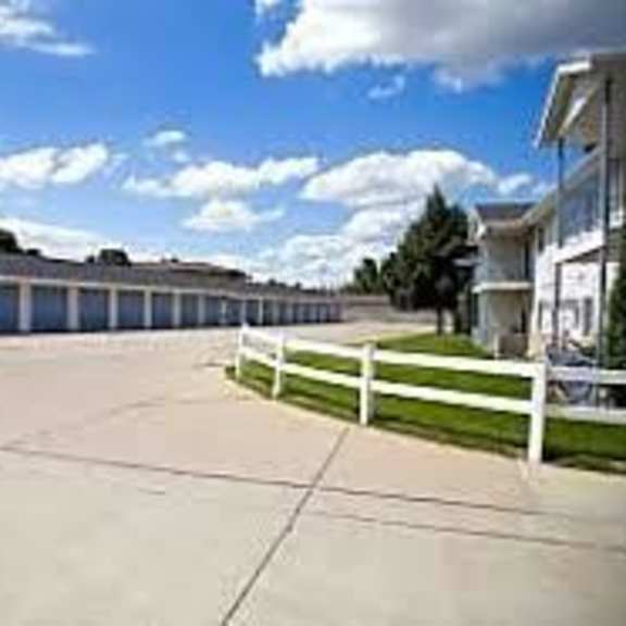 a parking lot with a white fence and a building in the background.
